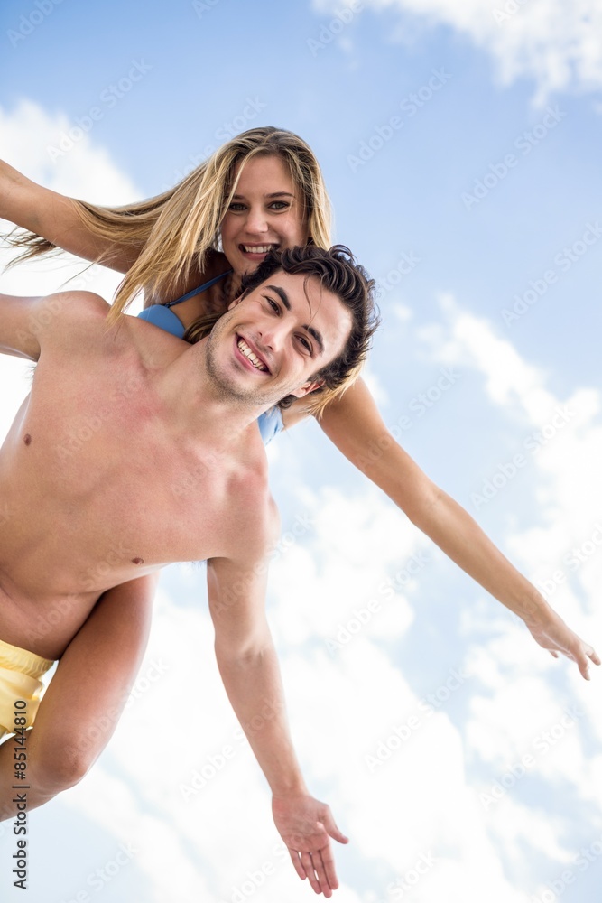 Handsome man giving piggy back to his girlfriend Handsome man giving piggy back to his girlfriend