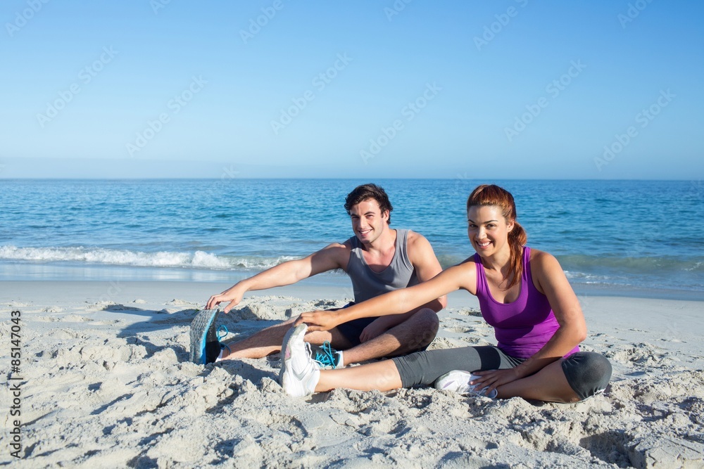 Fototapeta premium Happy couple stretching together beside the water