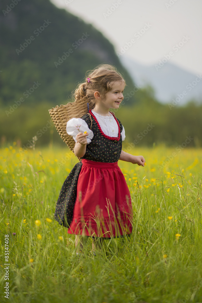 Bambina nel campo di fiori con gerla