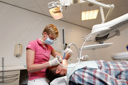 man is getting his teeth checked by the dental hygienist