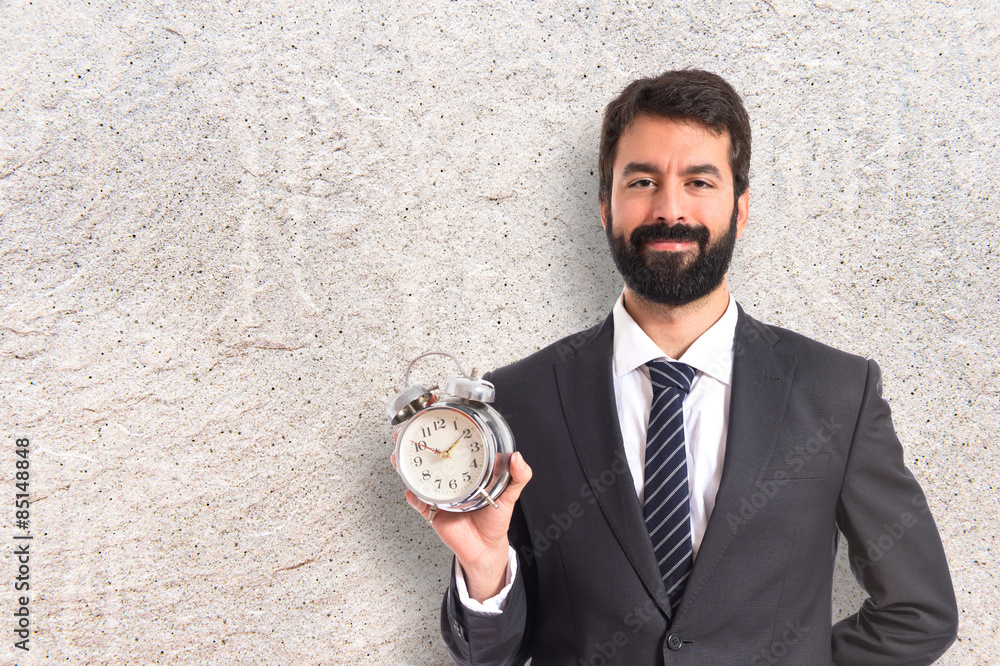 Businessman holding a clock over white background Businessman holding a clock over white background