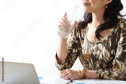 水を飲みながら仕事をする女性
