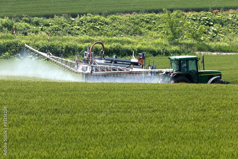 Obraz premium 美瑛の丘ブームスプレーヤによる畑への薬液散布作業