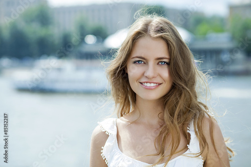 Young beautiful woman in green dress posing outdoors in sunny we