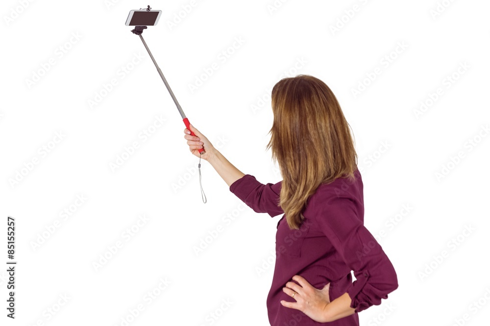 Wear view of pretty woman using a selfie stick Wear view of pretty woman using a selfie stick