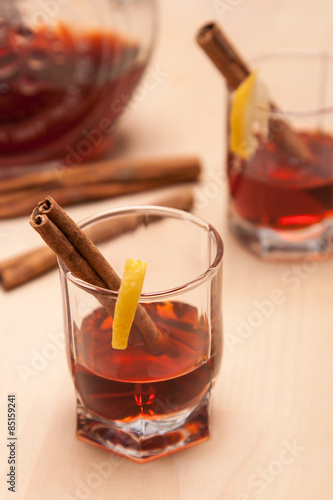 glass heating red liqueur with cinnamon sticks on table