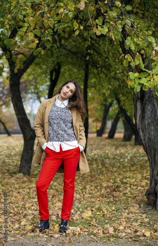 Young woman in fashion coat walking in autumn park © Andrey_Arkusha