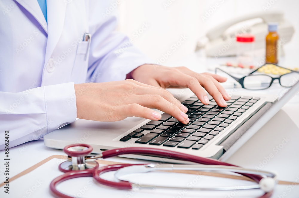 doctor typing information on the computer in office doctor typing information on the computer in office