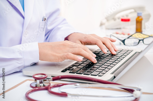 doctor typing information on the computer in office