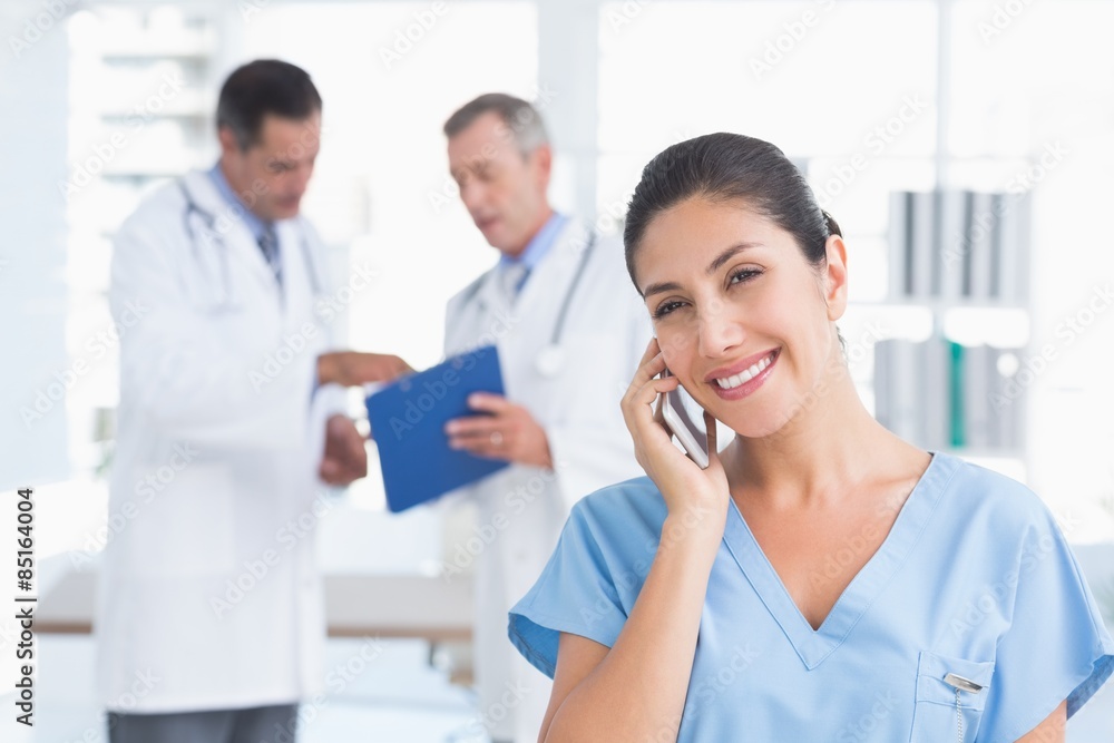 Nurse phoning while her colleagues working
