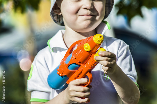boy outdoors shoots water from a water pistol