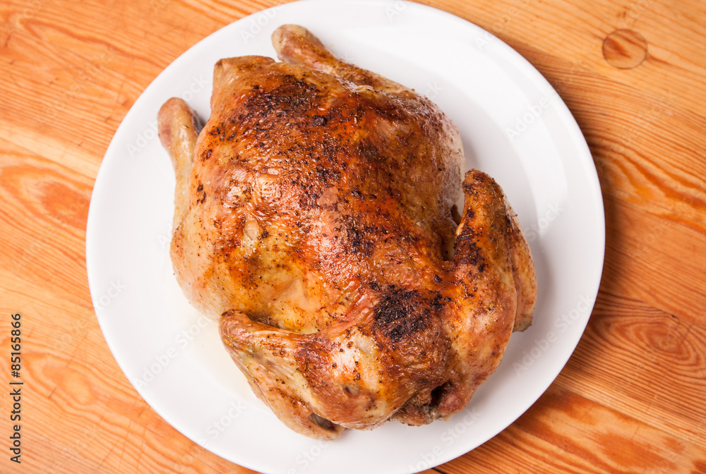 roast chicken on white plate and wooden roast chicken on white plate and wooden