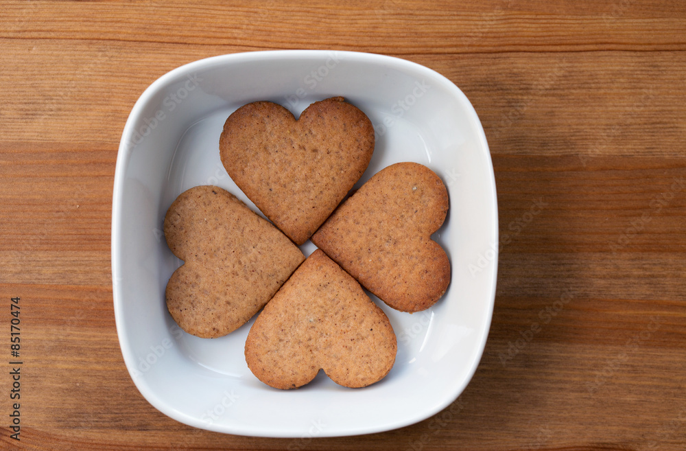 A white bowl with four heart-shaped homemade cookies inside A white bowl with four heart-shaped homemade cookies inside