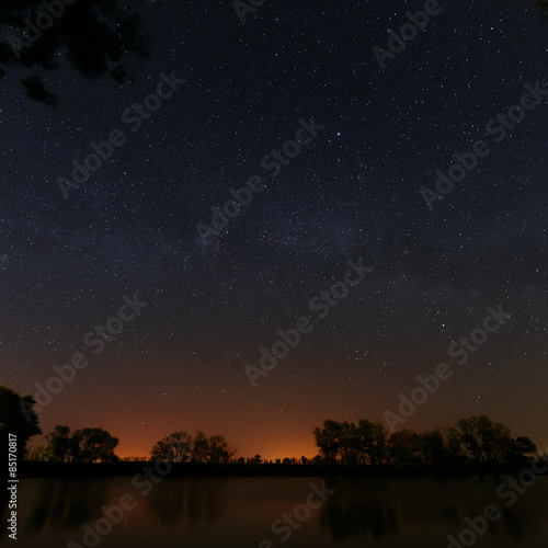 Smooth surface of forest lake on a background of the night sky 