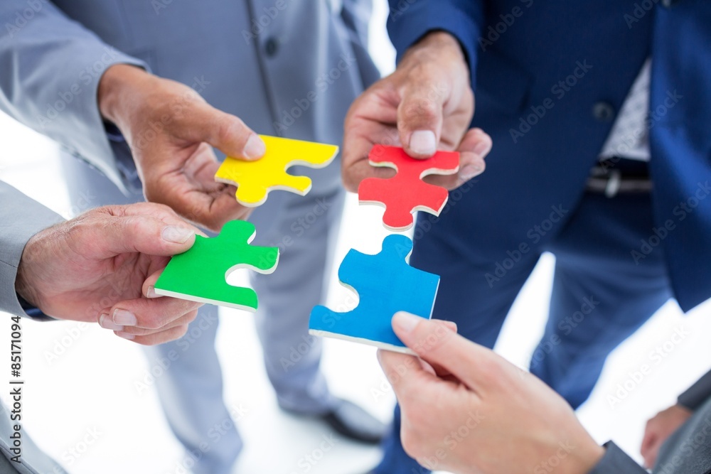 Business colleagues holding piece of puzzle Business colleagues holding piece of puzzle
