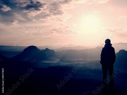Hiker stand on the sharp corner of sandstone rock in rock empires park and watching over the misty and foggy morning valley to Sun. © rdonar