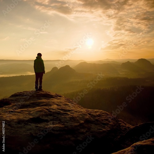 Girl stand on the sharp corner of sandstone rock in rock empires park and watching over the misty and foggy morning valley to Sun. Beautiful moment the miracle of nature