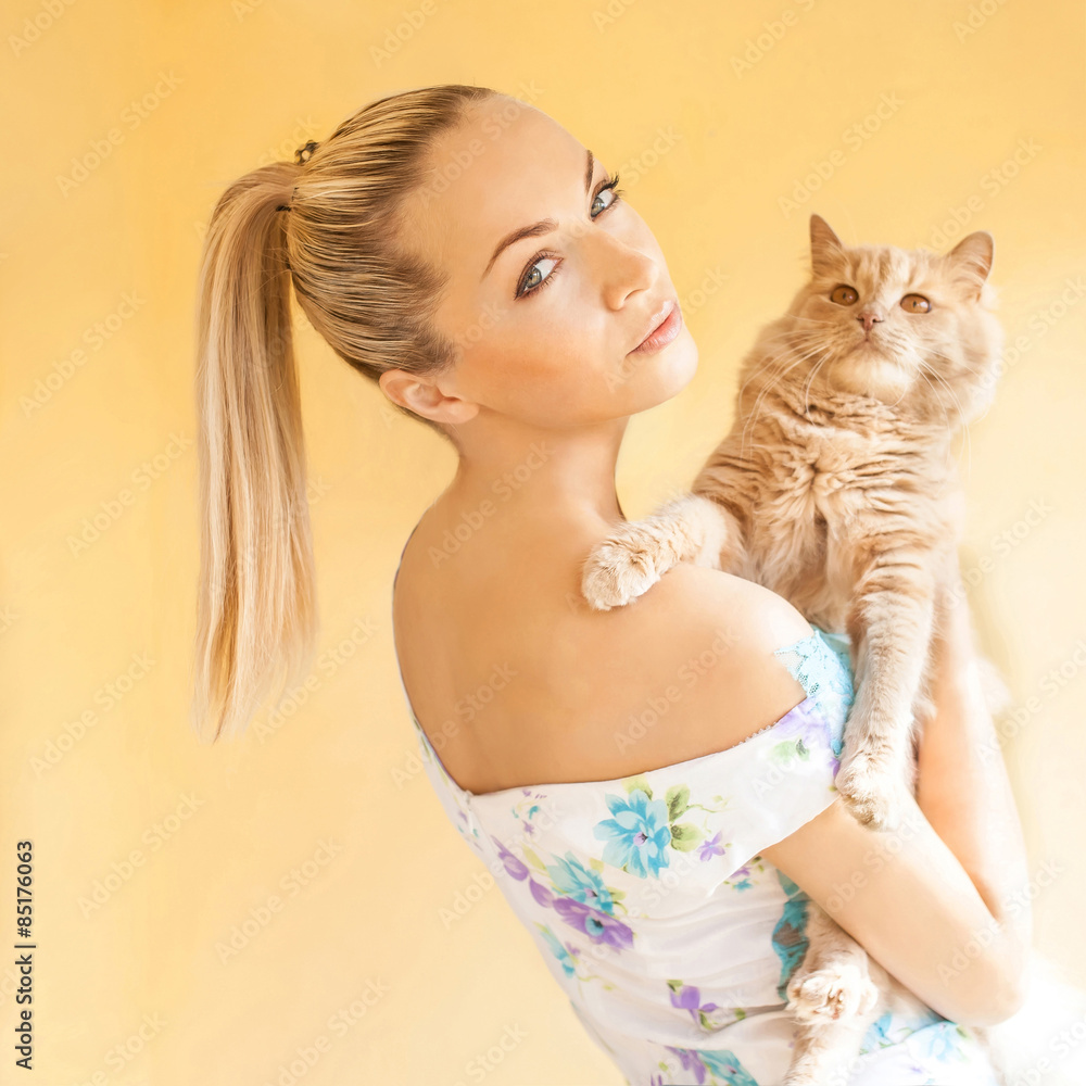 Girl with a cat in her arms an orange background