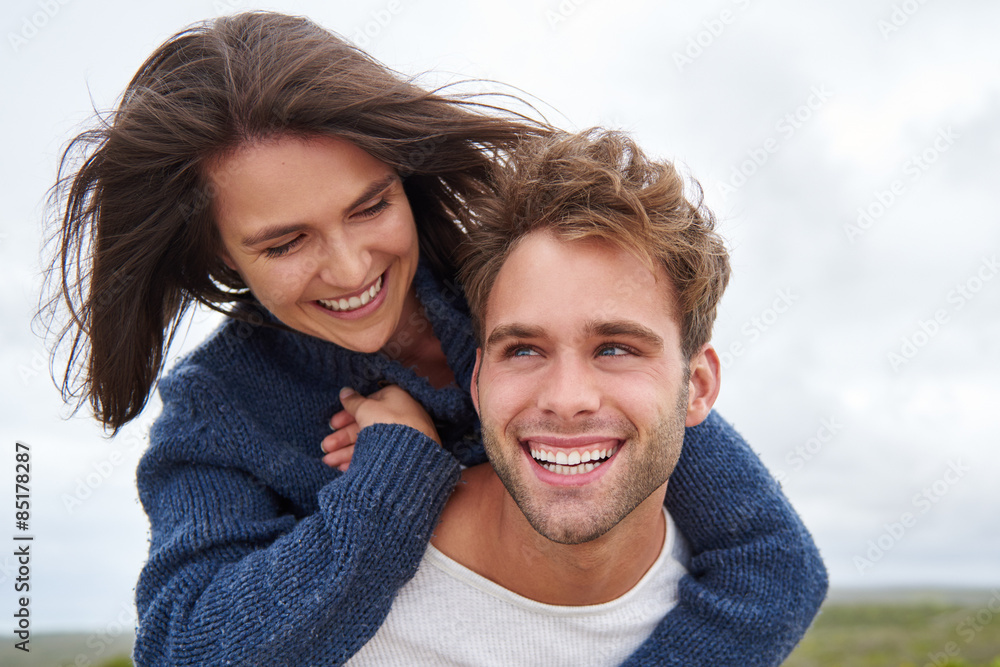 Young guy with a big smile piggybacking his girlfriend Young guy with a big smile piggybacking his girlfriend