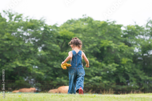 オーバーオールを着てテディーベアーで遊ぶ女の子