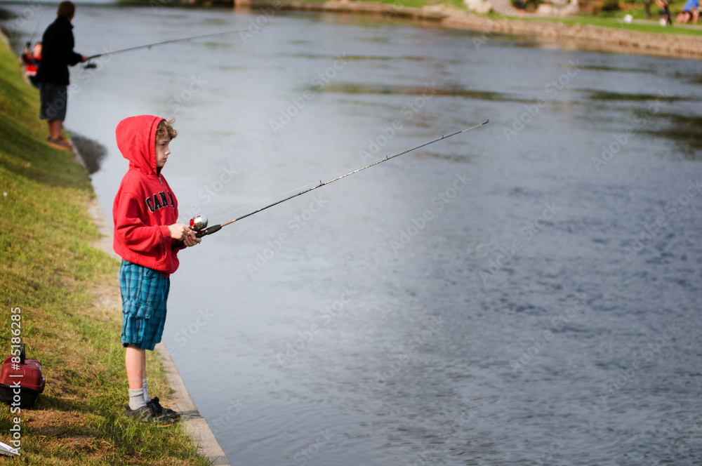 child on the bank of a river fishing child on the bank of a river fishing