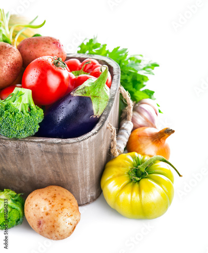 Fresh vegetables in wooden bucket with greens. Isolated on