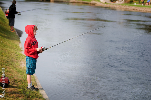 child on the bank of a river fishing