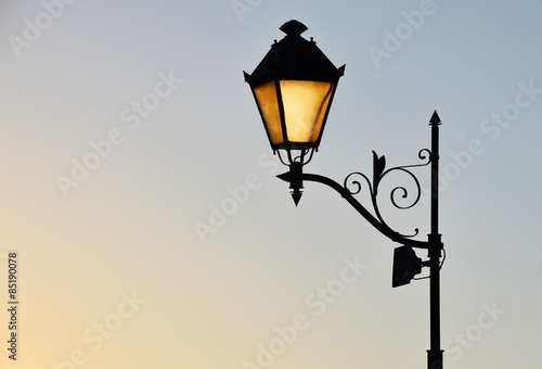 фотографія Street antique style lamp post with effect of shine from low light of sunset