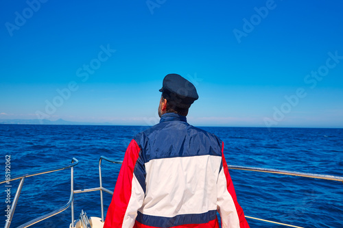 rear sailor cap man sailing sea ocean in a boat © lunamarina