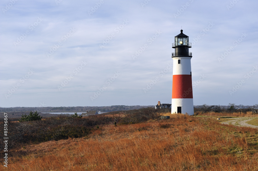 Sankaty Head Lighthouse Nantucket Cape Cod Massachusetts in the autumn with fall colors. It is a red and white striped light house on a bluff overlooking the sea. Copy space in the blue sky. 