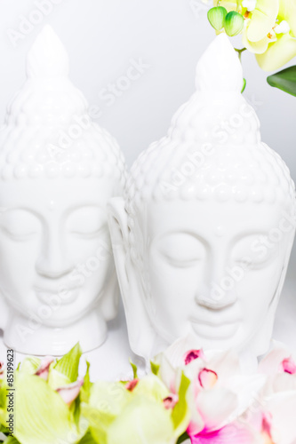 Two decorative statues of Buddha with orchids