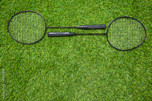 Two badminton rackets lying togeather on the grass