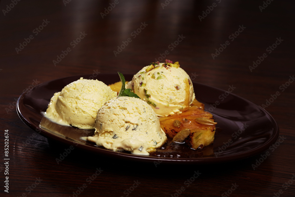 Serving of delicious home made vanilla ice cream with pistachio nuts, grilled pineapple and caramel topping Serving of delicious home made vanilla ice cream with pistachio nuts, grilled pineapple and caramel topping
