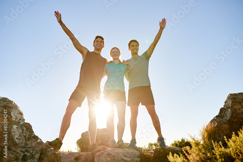 Athletic friends posing triumphantly on a mountain together