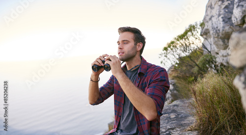 Young man searching for sights with his binoculars outdoors