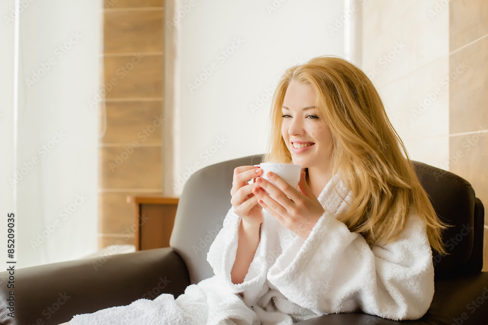 Beautiful blonde girl in a white robe drinking from cups and sm Beautiful blonde girl in a white robe drinking from cups and sm