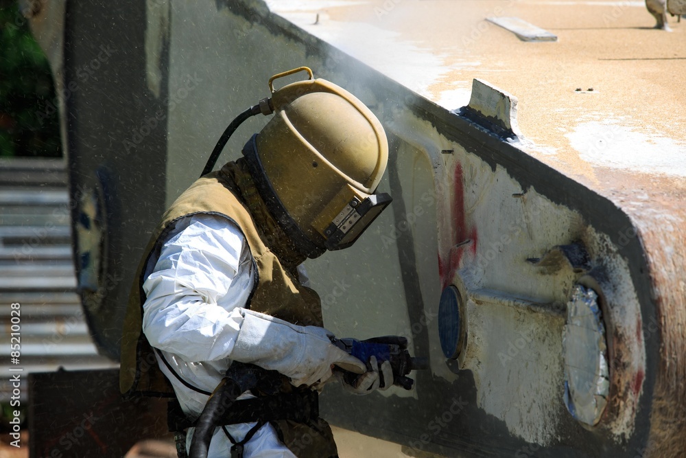 Fotografie Worker is remove paint by air pressure sand blasting