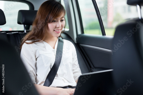Beautiful asian young woman using laptop in car