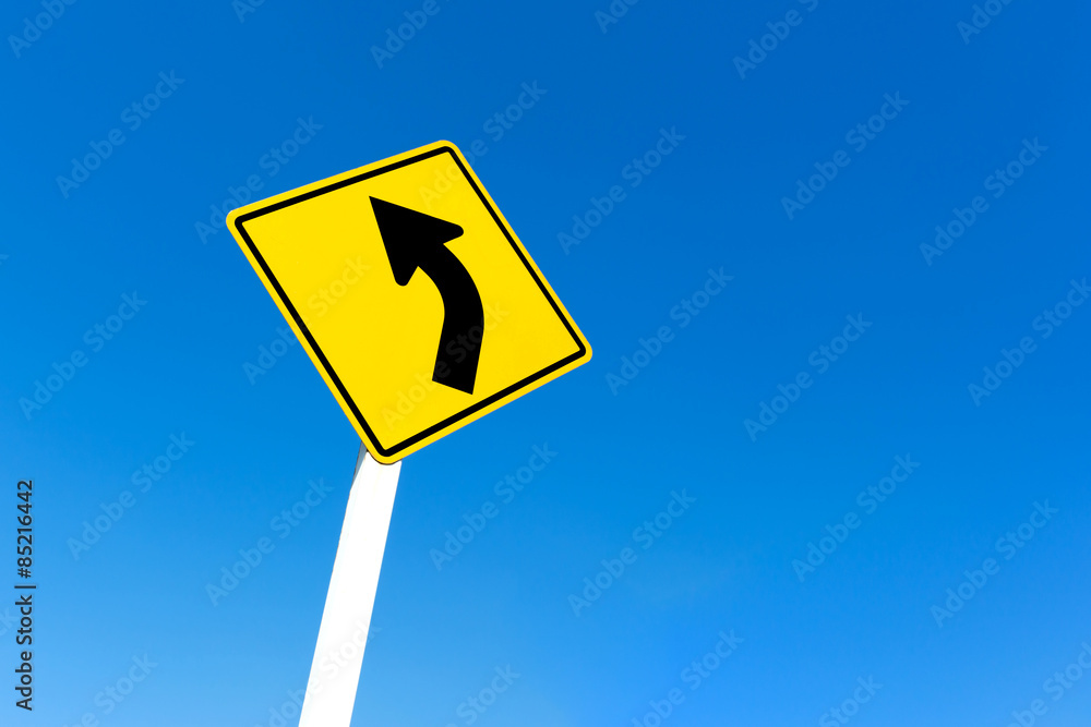 Yellow traffic left curve sign on blue sky background. Yellow traffic left curve sign on blue sky background.