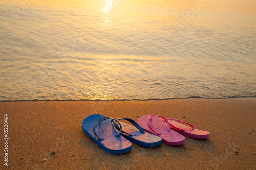Romantic beach scene. Female and male flip flpp sandals on the beach