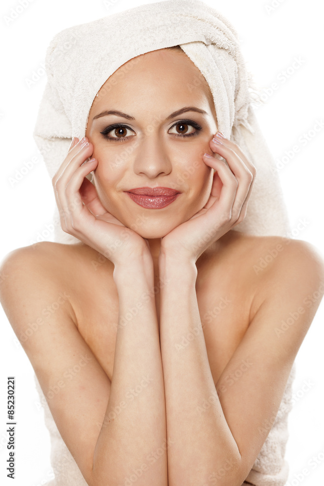 smiling young woman with a towel on her head posing on a white smiling young woman with a towel on her head posing on a white
