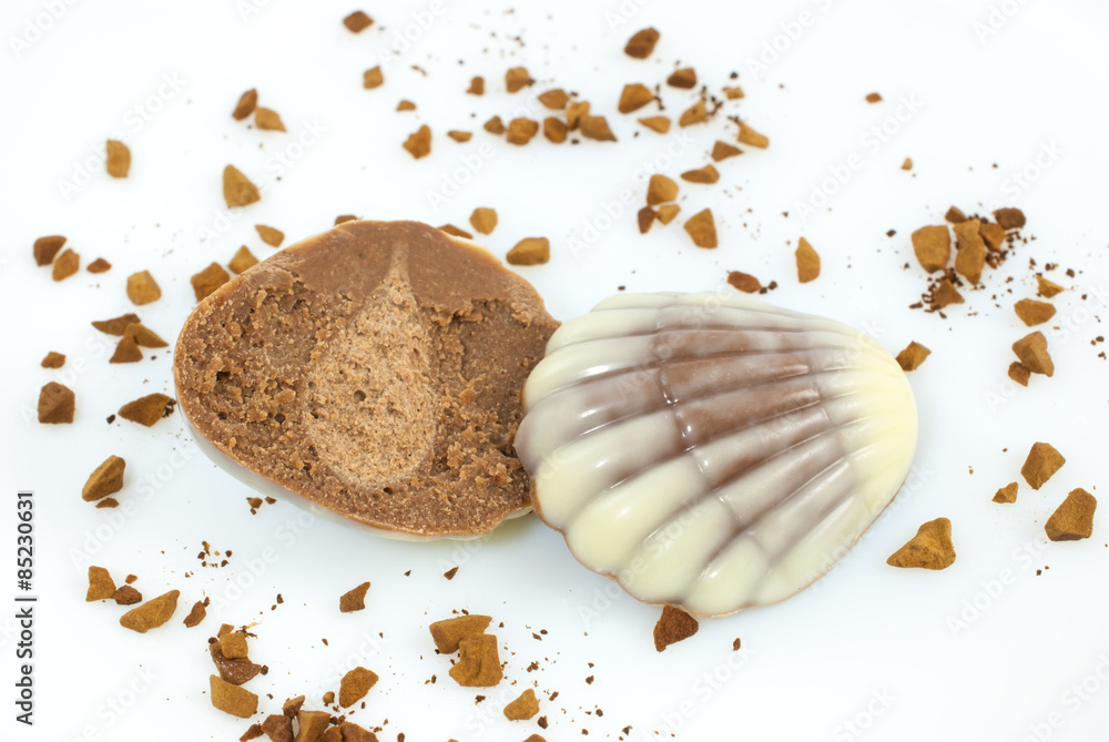 Sliced praline in seashell form and ground coffee on white background Sliced praline in seashell form and ground coffee on white background