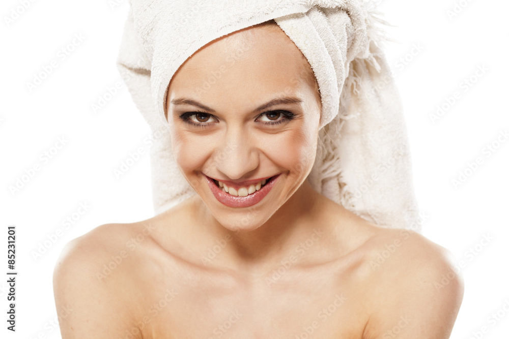 smiling young woman with a towel on her head posing on a white