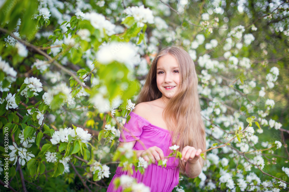 Beautiful toddler girl in pink dress stay in blossom flowers Beautiful toddler girl in pink dress stay in blossom flowers