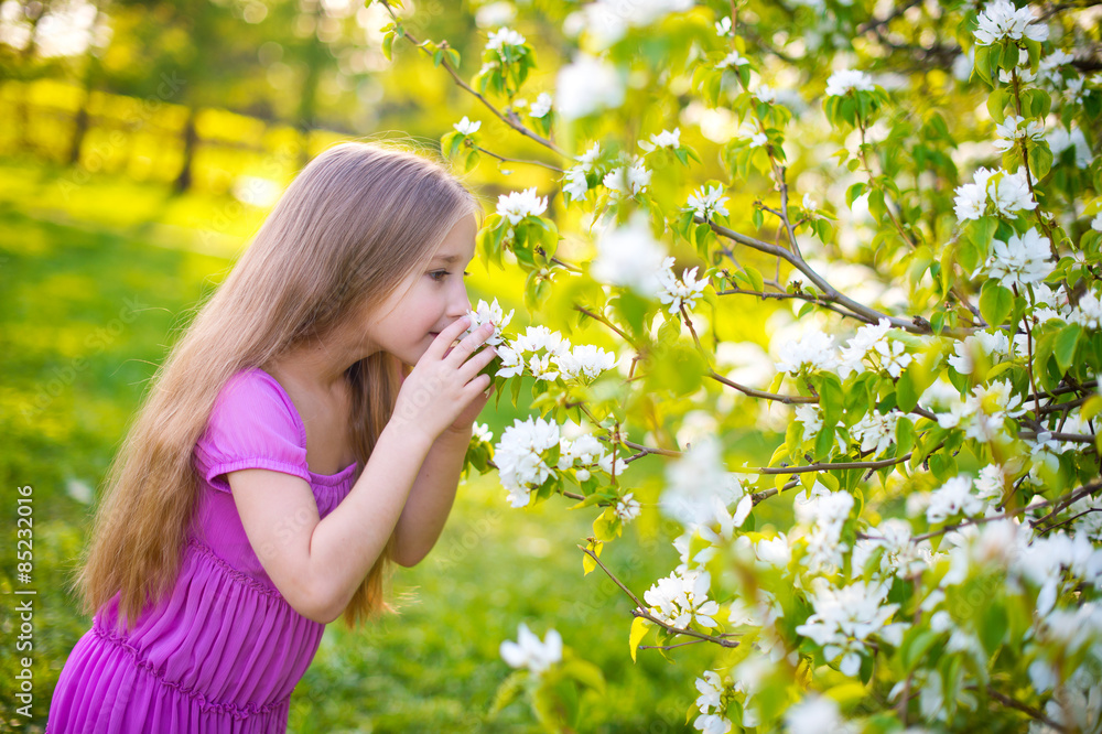 Beautiful toddler girl in pink dress stay in blossom flowers Beautiful toddler girl in pink dress stay in blossom flowers