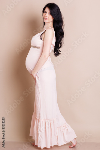 Studio portrait of beautiful pregnant woman holding her belly