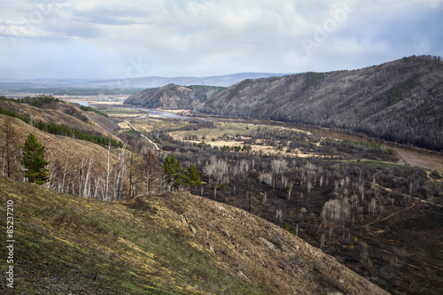 The Siberian river between hills, early spring