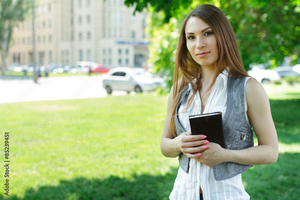 Business woman with paper notebook standing in the park on conference Business woman with paper notebook standing in the park on conference