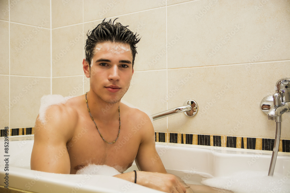 Handsome young man in bathtub at home having bath Photos Adobe Stock