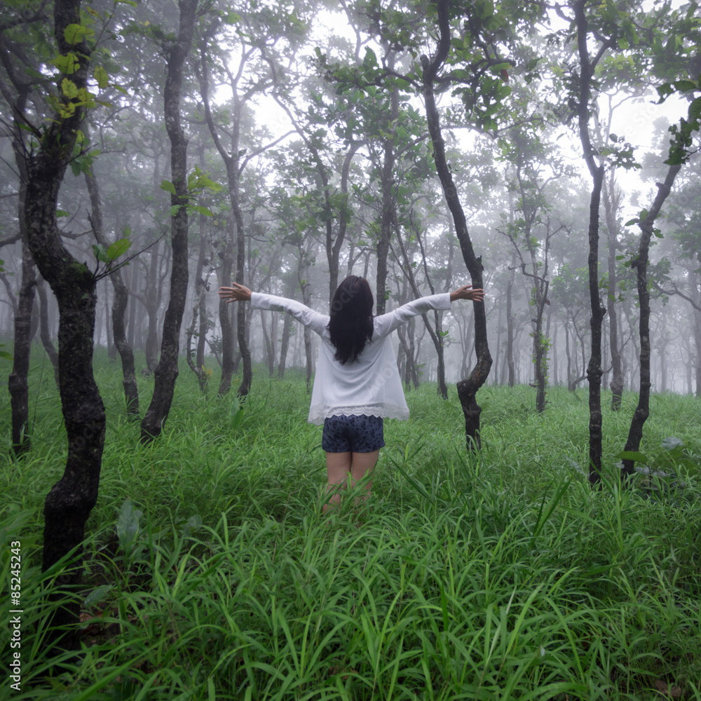 woman with hands up in forest